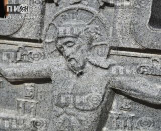 Памятник в форме резного креста с объёмным изображением распятия.